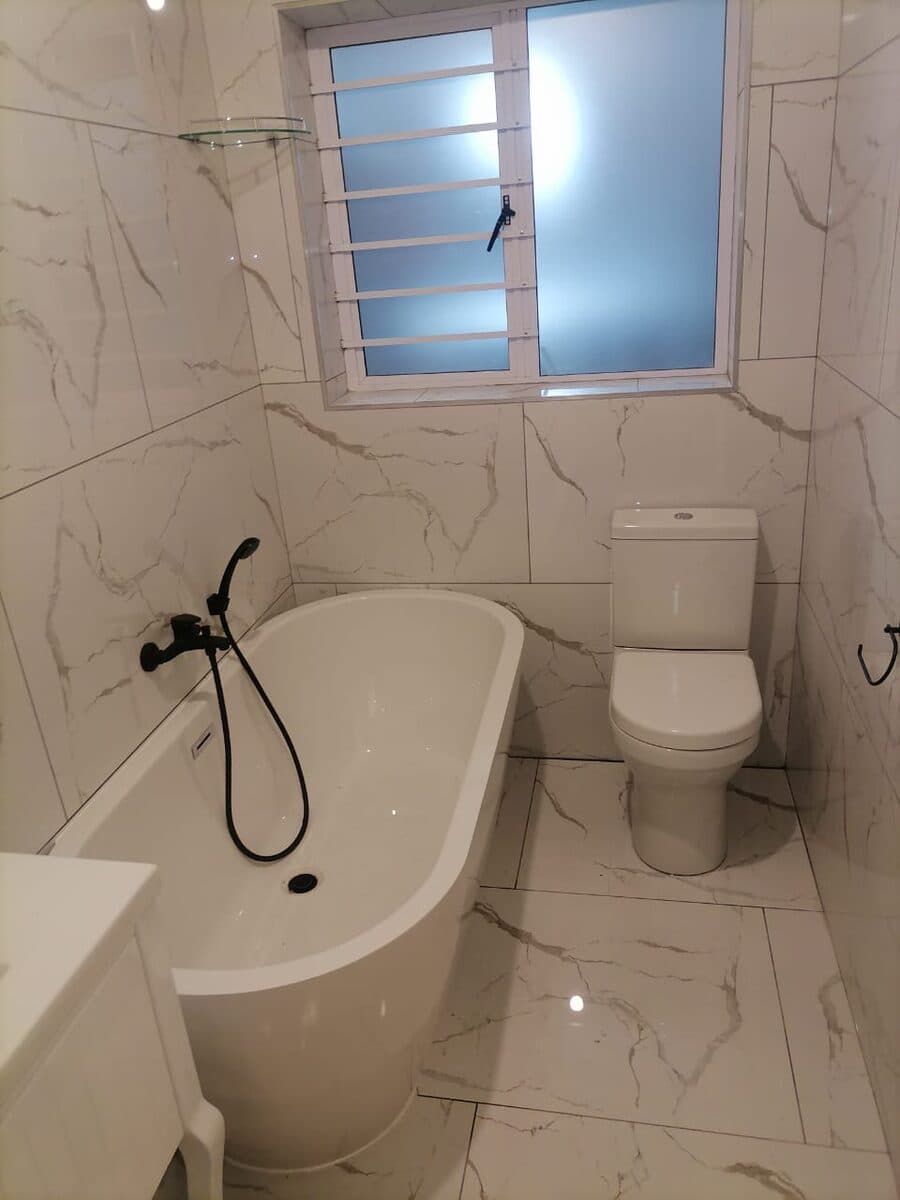 Completed bathroom installation with new bath, toilet and tiling